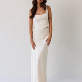 This is the Conrad Set in Ivory. This is a two piece satin set with a fitted, corseted top with thick straps and a delicate tie at the bust and a slight basque waist. It comes with a floor length satin column skirt.