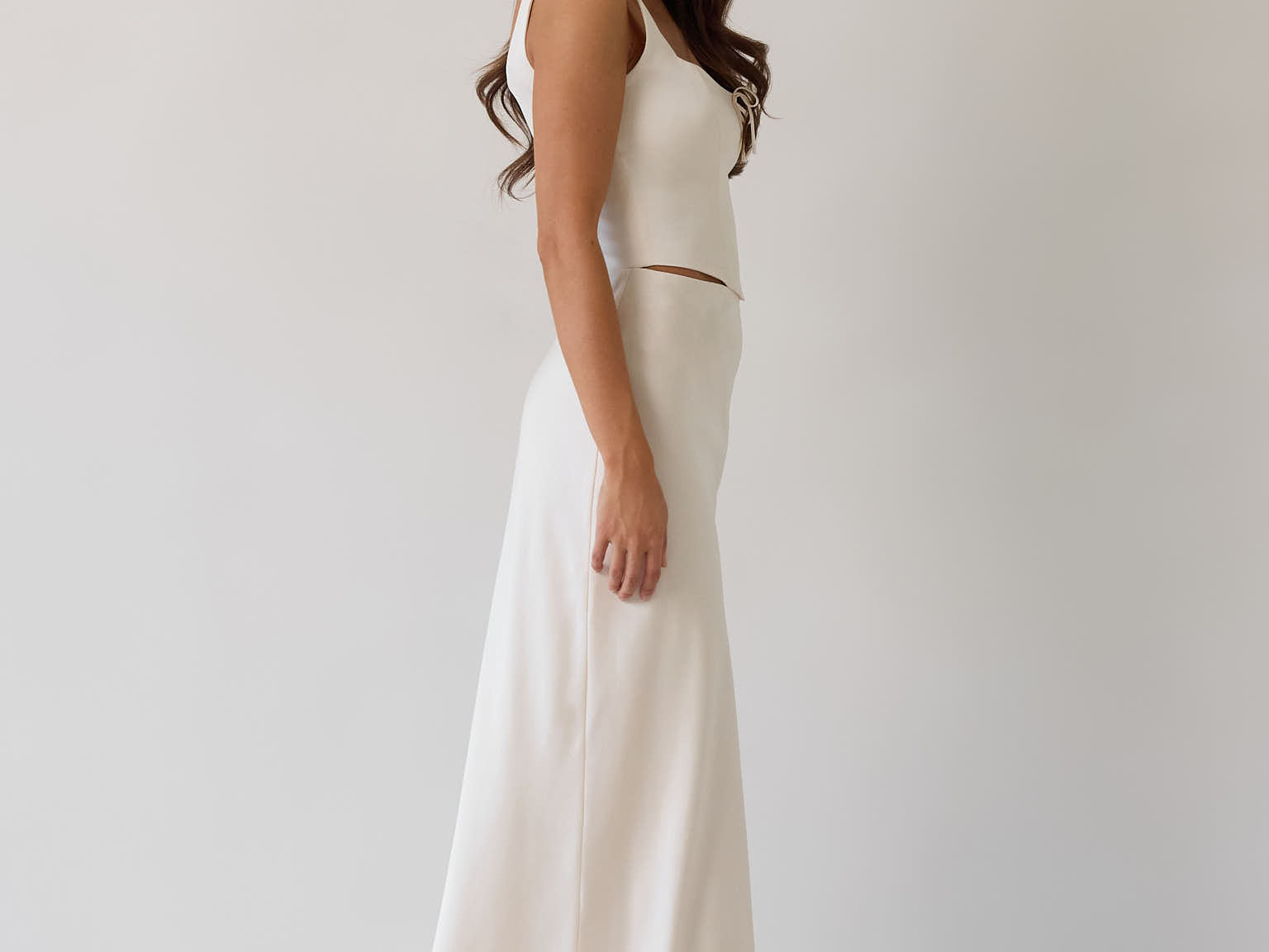 This is the Conrad Set in Ivory. This is a two piece satin set with a fitted, corseted top with thick straps and a delicate tie at the bust and a slight basque waist. It comes with a floor length satin column skirt.