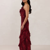 Side shot of model wearing the Majorca Dress in Garnet. A full length flowy guesting dress with a deep v neckline and ruffle details. Garnet is a dark red floral print.