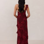 Back shot of model wearing the Majorca Dress in Garnet. A full length flowy guesting dress with a deep v neckline and ruffle details. Garnet is a dark red floral print.