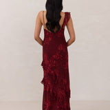 Back shot of model wearing the Majorca Dress in Garnet. A full length flowy guesting dress with a deep v neckline and ruffle details. Garnet is a dark red floral print.