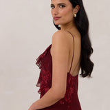 Side shot of model wearing the Majorca Dress in Garnet. A full length flowy guesting dress with a deep v neckline and ruffle details. Garnet is a dark red floral print.