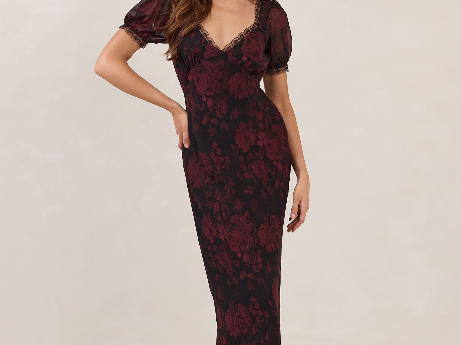 Woman wearing a burgundy floral dress with lace detail on a white background.