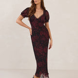 Woman wearing a burgundy floral dress with lace detail on a white background.