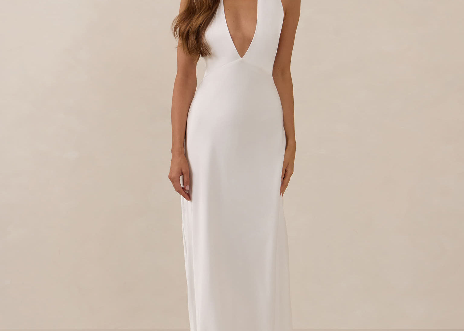 Woman wearing a white halter neck dress against a beige background
