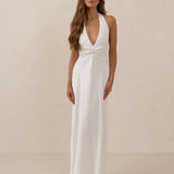 Woman wearing a white halter neck gown against a beige background