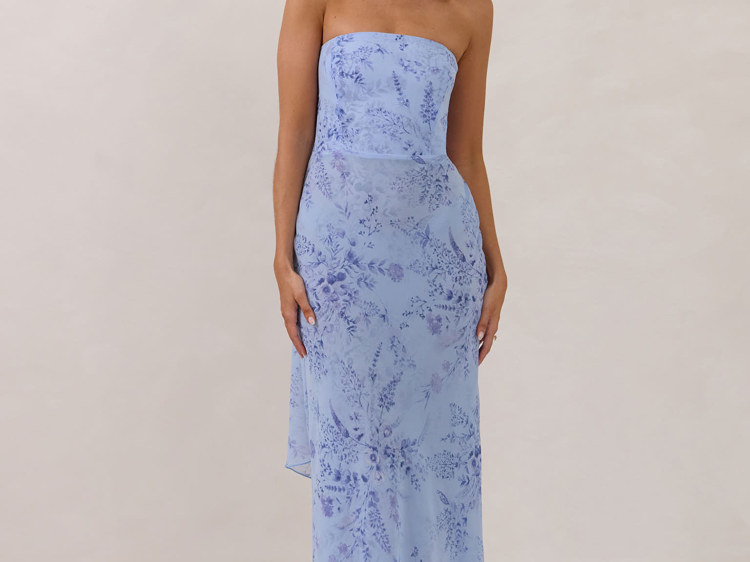 Model wearing a strapless chiffon blue floral dress with a matching scarf. 