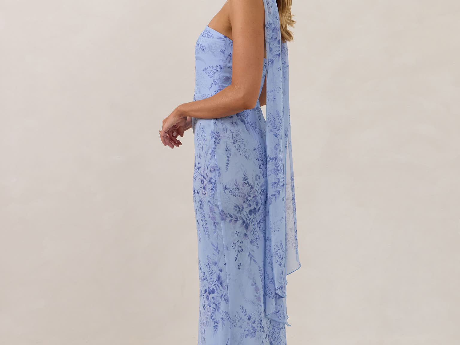 Model wearing a strapless chiffon blue floral dress with a matching scarf. 
