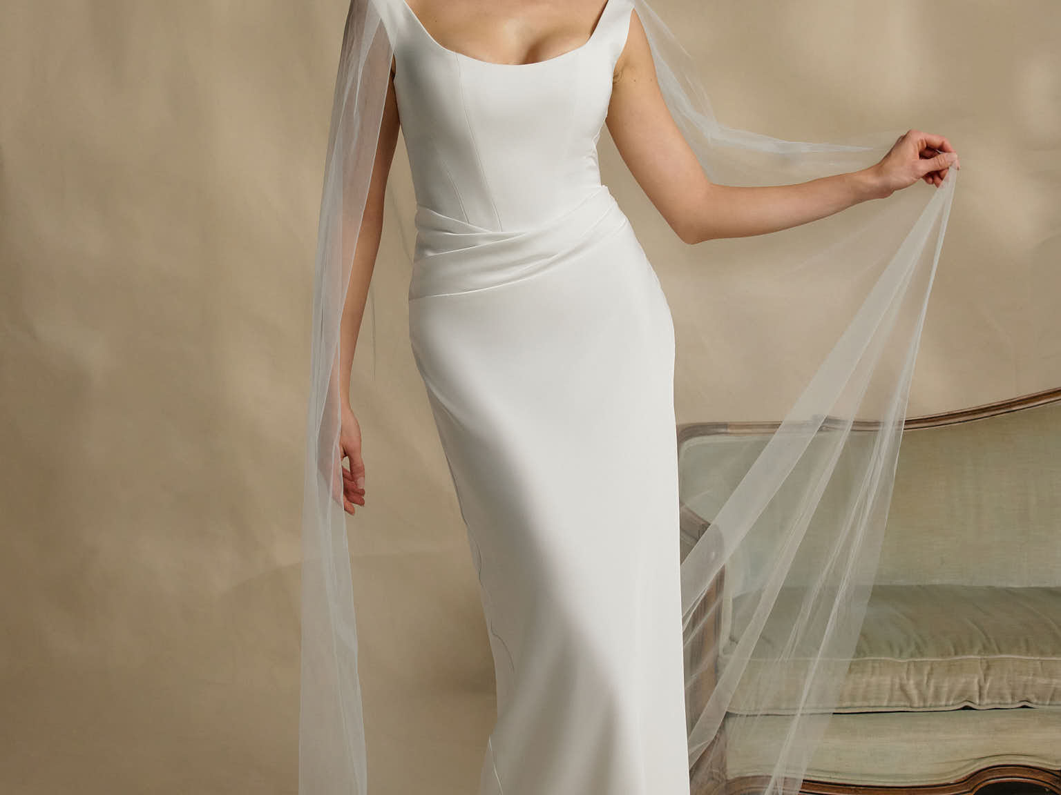 Woman in a white wedding dress with a long veil against a neutral background