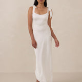 Woman wearing a white sleeveless dress against a beige background