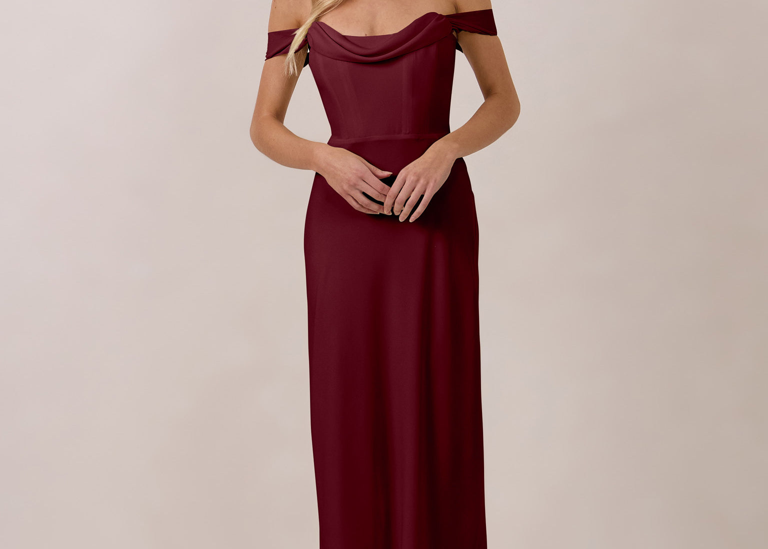 Woman wearing a burgundy off-shoulder dress against a plain background